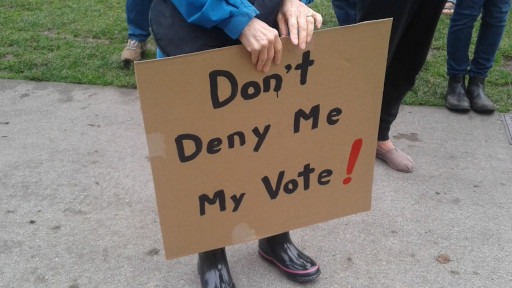 Protester holds sign reading "Dont Deny Me My Vote!"
