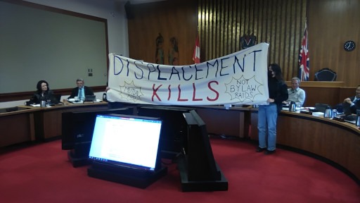 Captured during a council meeting at Victoria City Hall in April 2024, at which advocates held a banner reading "Displacement Kills".